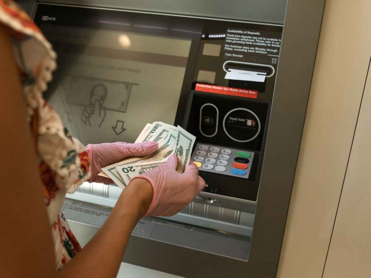 person counting money in front of atm