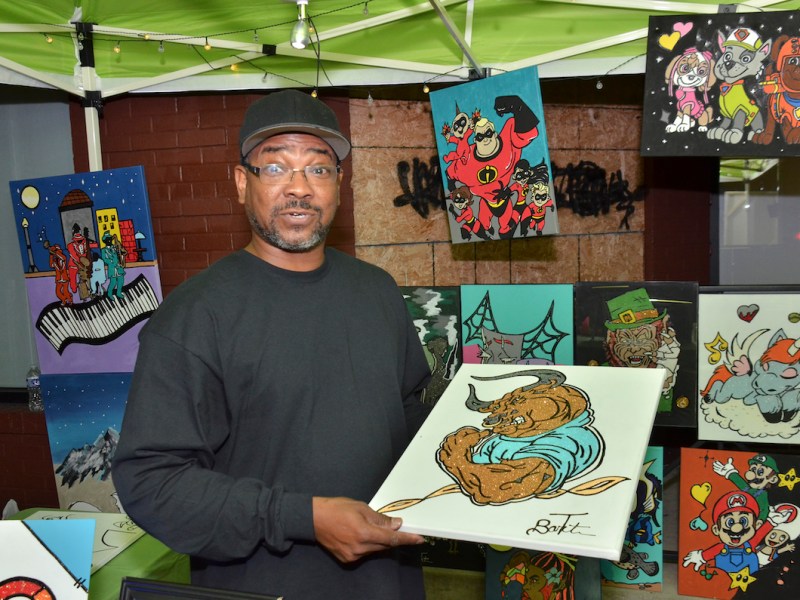 **FILE** Terrance Barton of F&T Creative Art holds one of his pieces of art where he was set up in Ward 2 for Art All Night 2022. (Jacques Benovil/The Washington Informer)