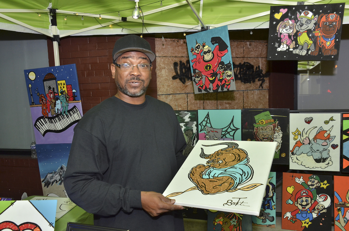 **FILE** Terrance Barton of F&T Creative Art holds one of his pieces of art where he was set up in Ward 2 for Art All Night 2022. (Jacques Benovil/The Washington Informer)