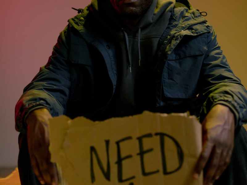 sitting homeless man holding cardboard