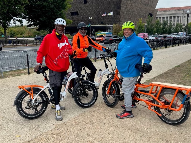 Brothers Lester Austin (right) and Hasker Austin (center) stop for a photo in front of the National African American History Museum while touring D.C. on e-bikes with a cousin, Lester Fultz, who was visiting from Cleveland. (Courtesy of Lester Austin)
