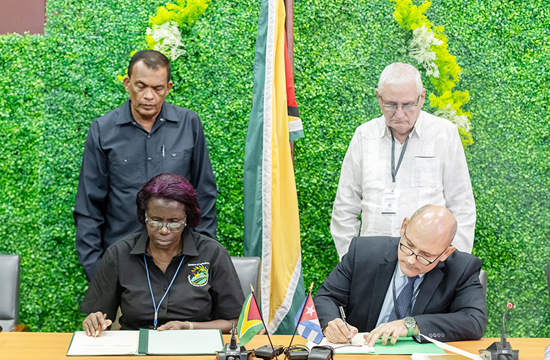 Permanent Secretary of the Ministry of Agriculture, Delma Nedd (front left), and Cuban Ambassador to Guyana, Jorge Francisco Soberon Luis (front right) take part in the signing of a Memorandum of Understanding. (Courtesy of Delano Williams)