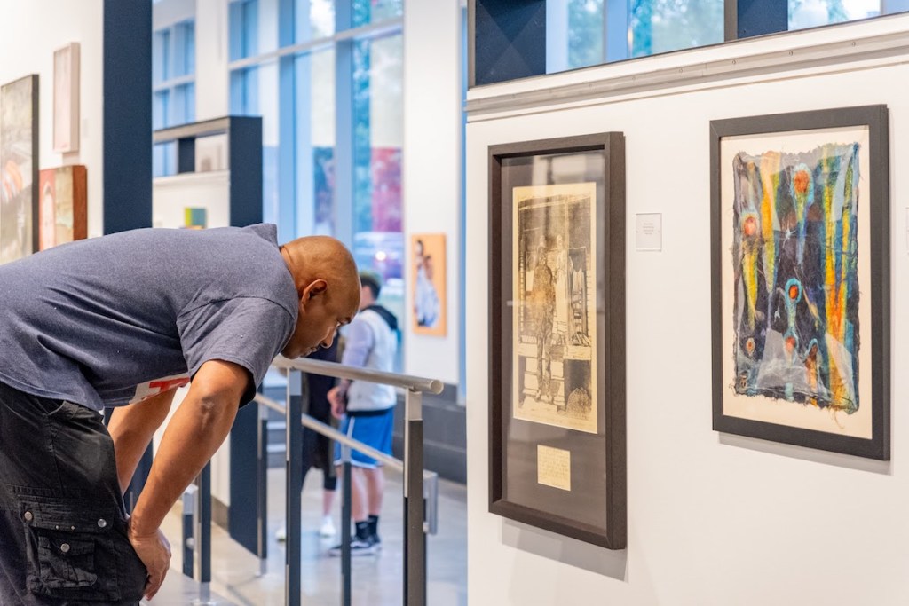 An attendee takes in art at the “DC Art Now 2023” at the 200 I (Eye) Street Galleries  in Southeast. (Ja’Mon Jackson/The Washington Informer)