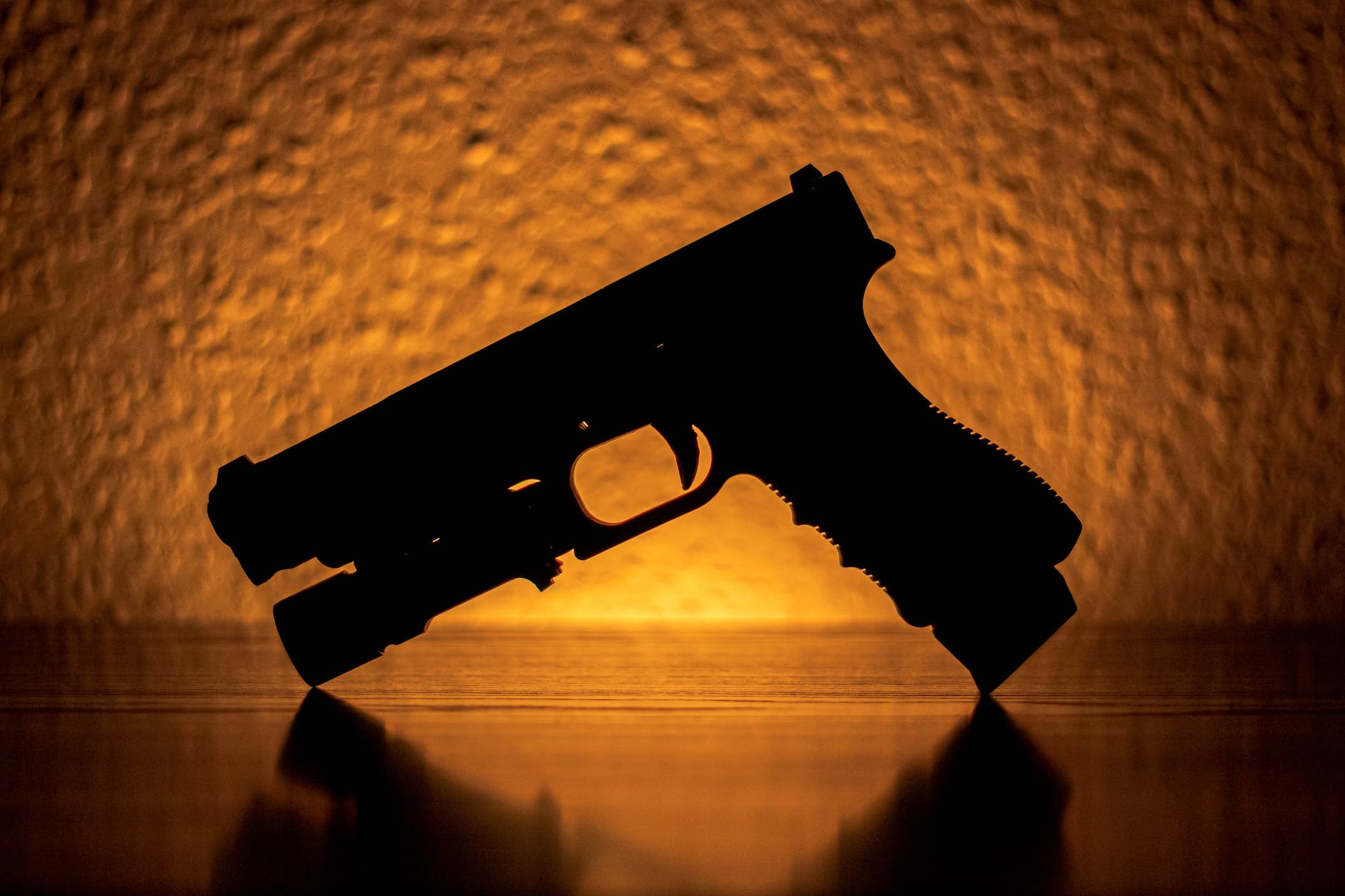 silhouette of a pistol near an orange light