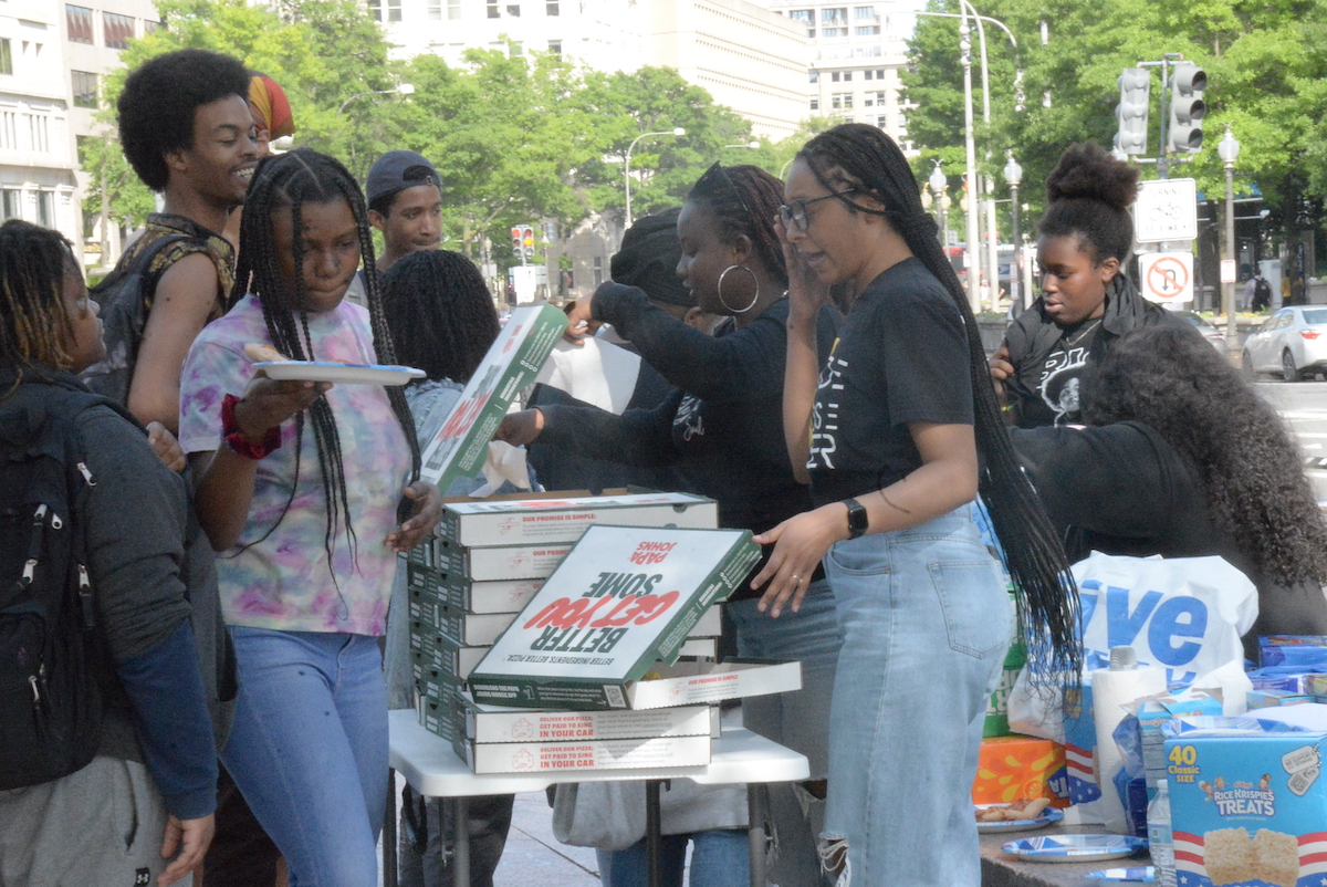 Black Swan Academy staff serve evening meals to young students, waiting for the "We All Rise When Black Youth Thrive" Rally on Freedom Plaza on May 13 at the John A. Wilson Building in Northwest D.C. (Roy Lewis/The Washington Informer)
