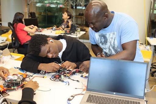 Oluwafemi "Femi" Oladosu, a doctoral student at Howard University, works with a high schooler at the Amazon Drone Academy at Howard University on June 27. (Eden Harris/The Washington Informer)