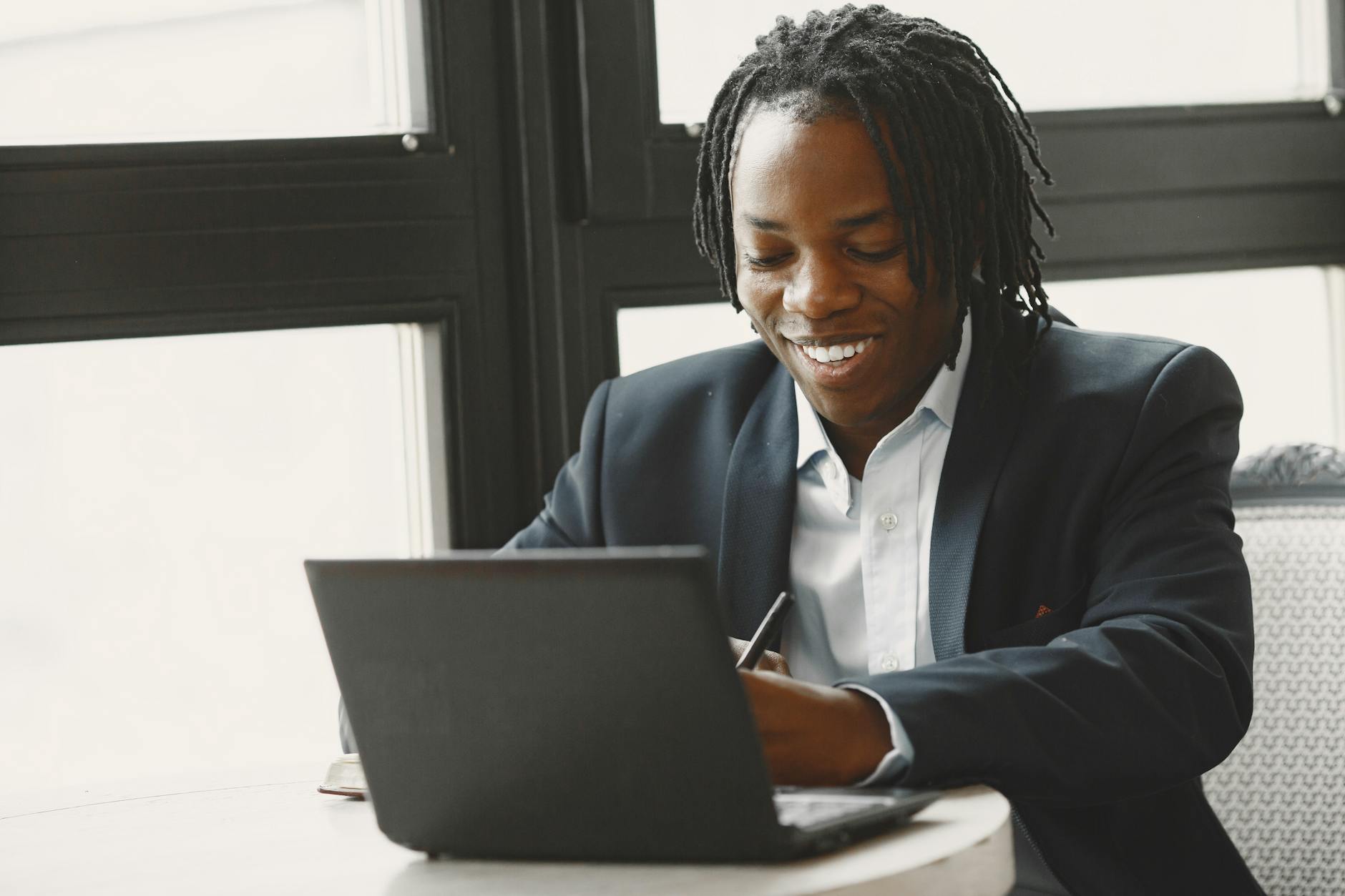 man in a suit using laptop and smiling