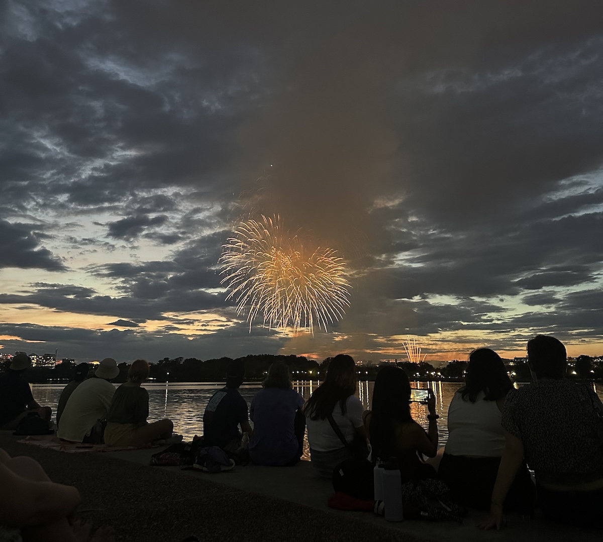 People sit by the Tidal Basin at the Thomas Jefferson Memorial in Washington, D.C., to watch the annual fireworks display on July 4, 2023. (Juan Benn Jr./The Washington Informer)