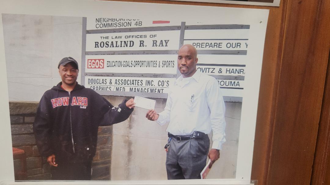 Walter Ray, founder of Education, Goals, Opportunity and Sports (EGOS), receives a donation from EGOS alumni Dante Baldeh. The organization is celebrating 30 years of providing opportunities for overlooked youth. (Courtesy of EGOS)