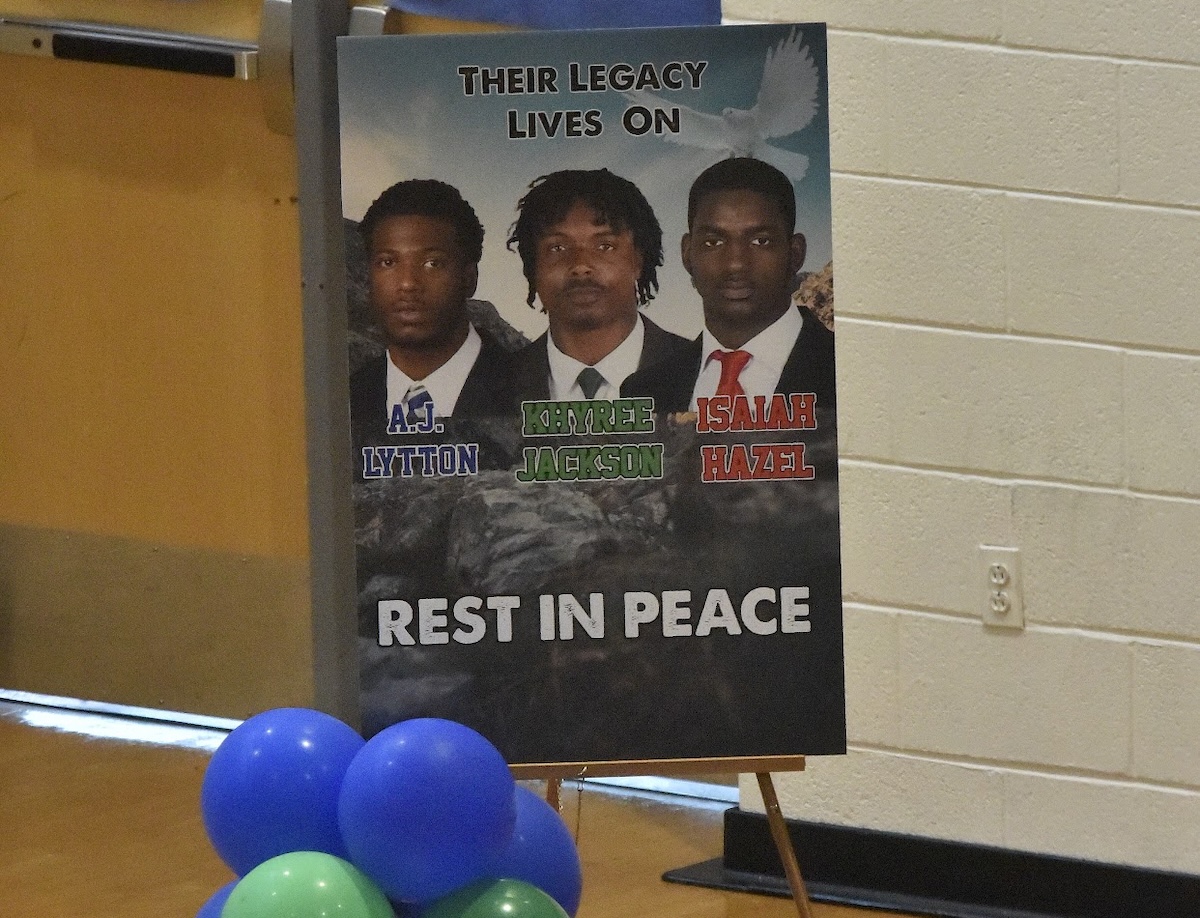 Behind the podium, a tribute image reading "Their Legacy Lives On" depicts friends Khyree Jackson, Anthony "AJ" Lytton, and Isaiah Hazel, who were killed in a car accident on July 6. (Robert R. Roberts/ The Washington Informer)